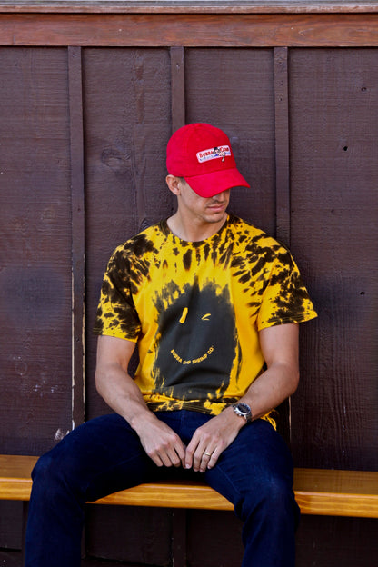 Man wearing Authentic Forrest Gump cap paired with Tie Dye Winking Smiley Face Tee from Bubba Gump.